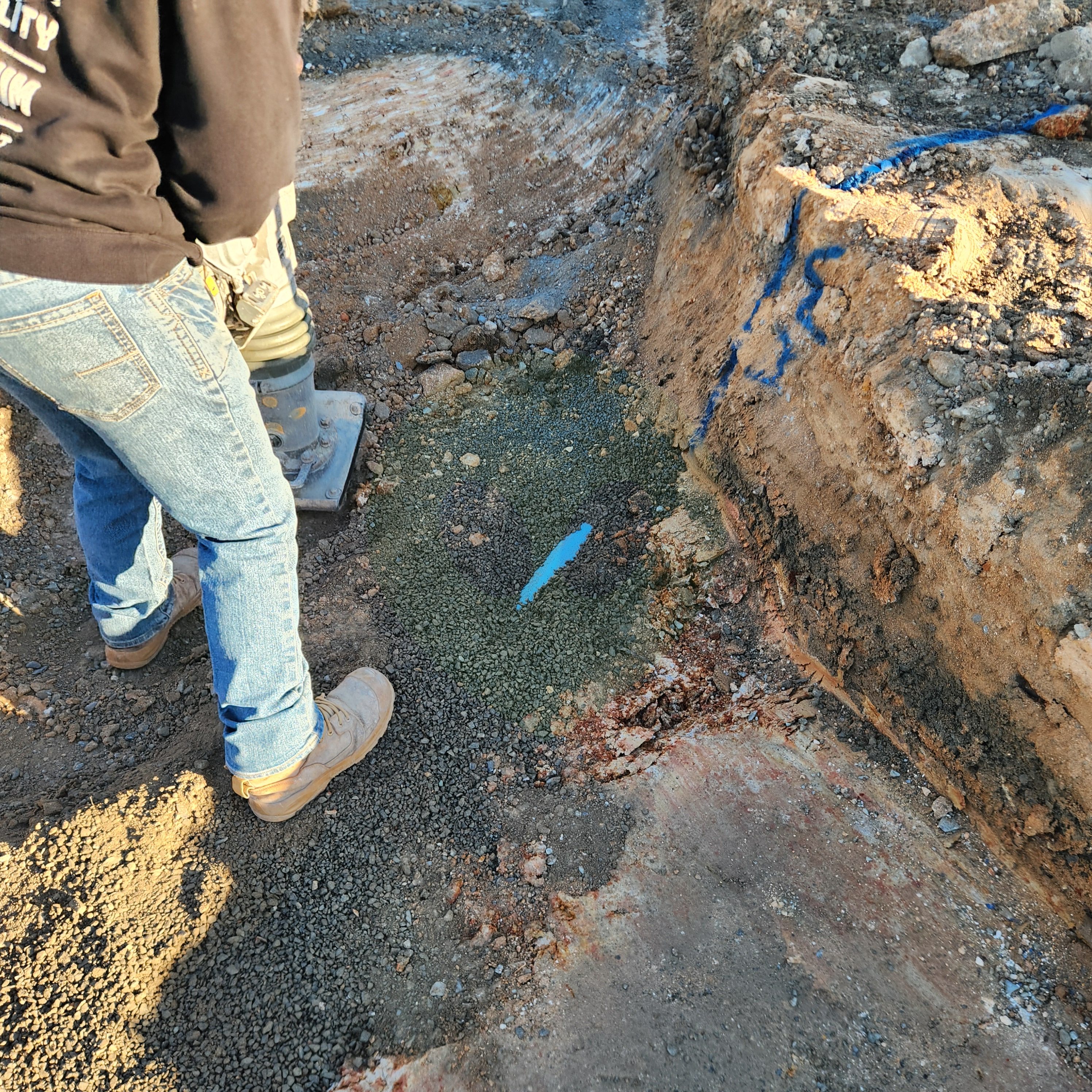 상수도관 옆에서 다지는 모습 — 파란 선(WM, Water Main)은 상수도관 표시